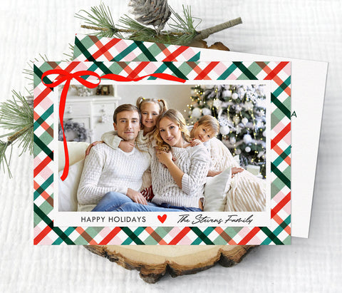 landscape oriented holiday card with single photo on a pink and green plaid background with a ribbon detail in upper left corner