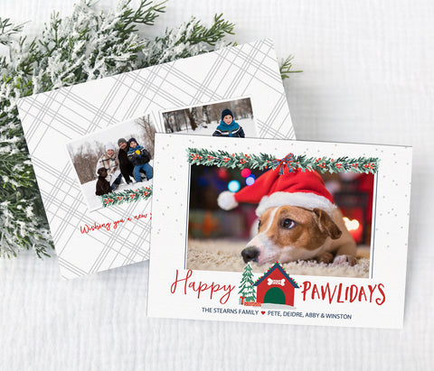 dog themed holiday card with single photo against a white background. traditional red and green christmas garland along the top and a dog house and christmas tree at the bottom. happy pawlidays wording