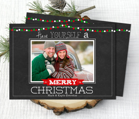 christmas photo card with black chalkboard background, single photo, and red and green holiday light strings along top